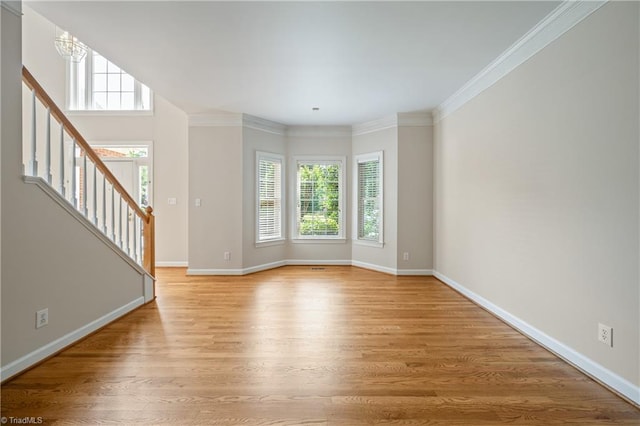unfurnished living room featuring healthy amount of natural light, light wood-style floors, stairway, baseboards, and ornamental molding