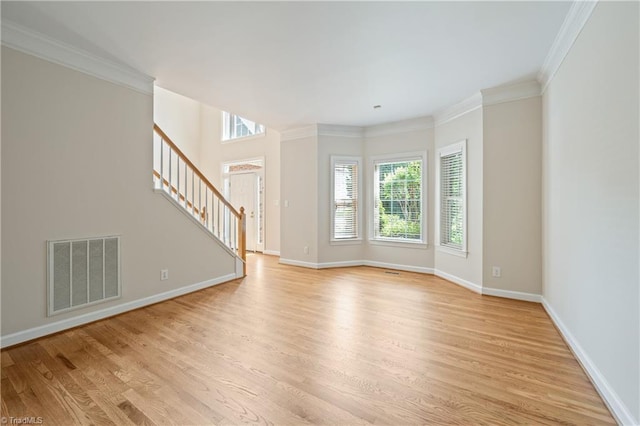 unfurnished living room featuring plenty of natural light, light wood finished floors, stairs, ornamental molding, and baseboards
