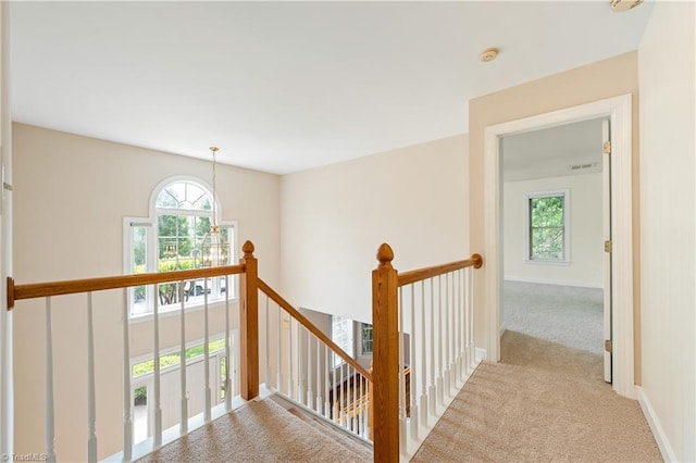 hall featuring carpet floors, an upstairs landing, and baseboards