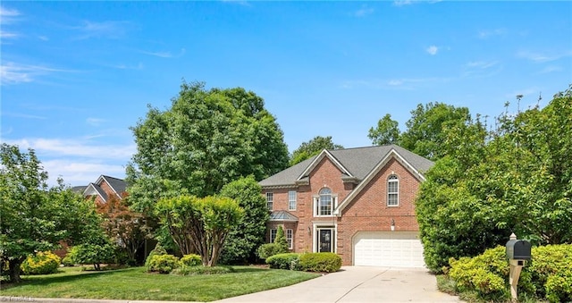 colonial house featuring concrete driveway, a garage, brick siding, and a front yard