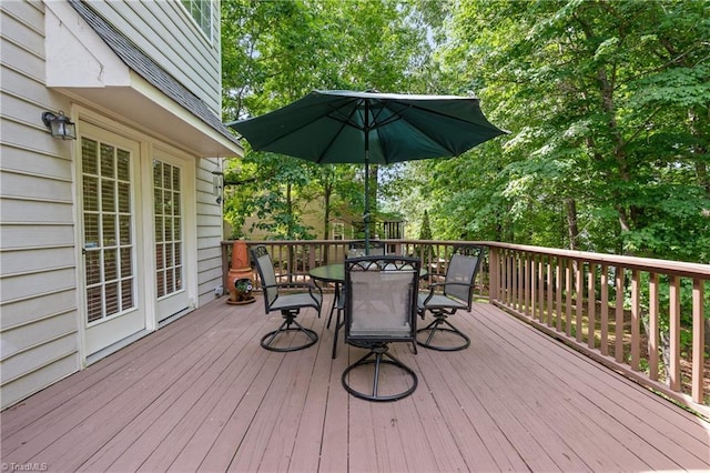 wooden deck featuring outdoor dining area and view of wooded area