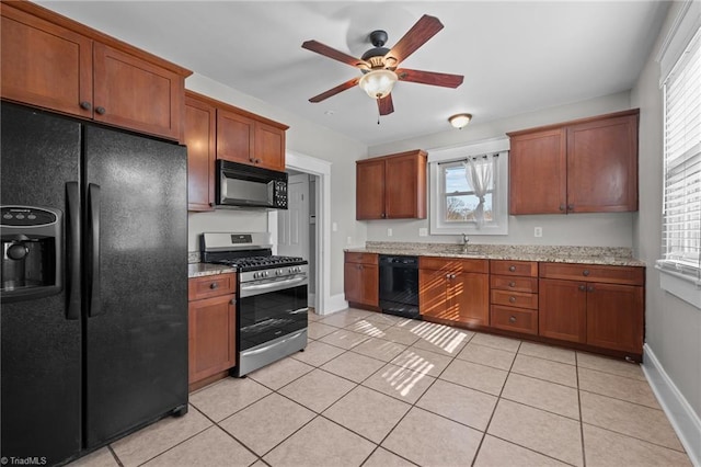 kitchen featuring light stone countertops, plenty of natural light, light tile patterned floors, and black appliances