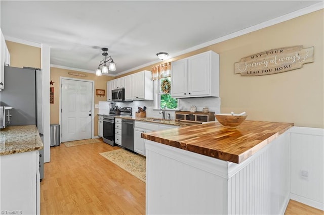 1044 Riverwood Rd, Lexington, NC 27292 - kitchen featuring a sink, stainless steel appliances, a peninsula, light wood-style floors, and white cabinets