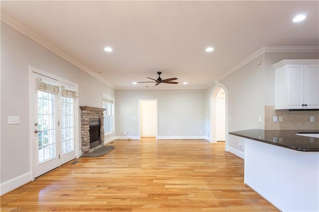 unfurnished living room featuring crown molding, ceiling fan, a fireplace, and light hardwood / wood-style floors