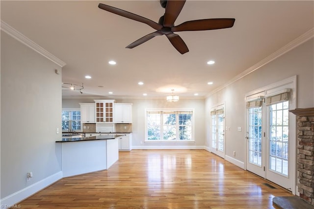 unfurnished living room featuring crown molding, sink, ceiling fan, and light hardwood / wood-style floors