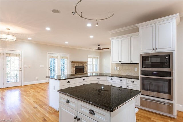 kitchen featuring black microwave, white cabinetry, oven, decorative backsplash, and ornamental molding