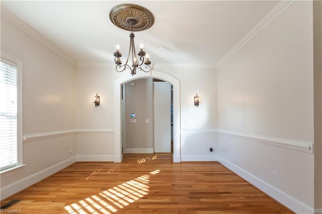 empty room featuring crown molding, wood-type flooring, and a chandelier