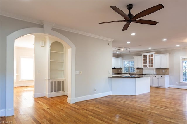 kitchen featuring backsplash, crown molding, light hardwood / wood-style flooring, and white cabinets