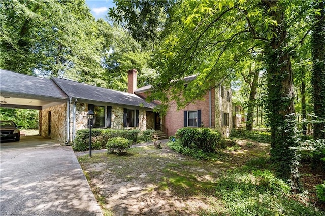 1204 Hobbs Rd, Greensboro, NC 27410 - view of front facade featuring concrete driveway, a chimney, stone siding, and an attached carport
