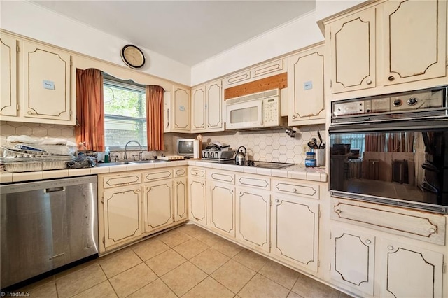 1204 Hobbs Rd, Greensboro, NC 27410 - kitchen featuring black appliances, tile counters, light tile patterned flooring, and backsplash