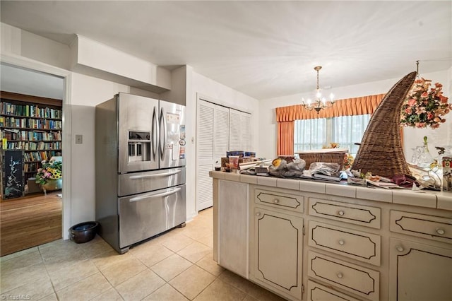 1204 Hobbs Rd, Greensboro, NC 27410 - kitchen with stainless steel fridge, tile countertops, a chandelier, light tile patterned floors, and decorative light fixtures