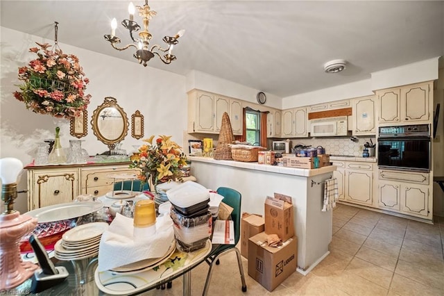 1204 Hobbs Rd, Greensboro, NC 27410 - kitchen featuring black oven, white microwave, a chandelier, a peninsula, and tile counters