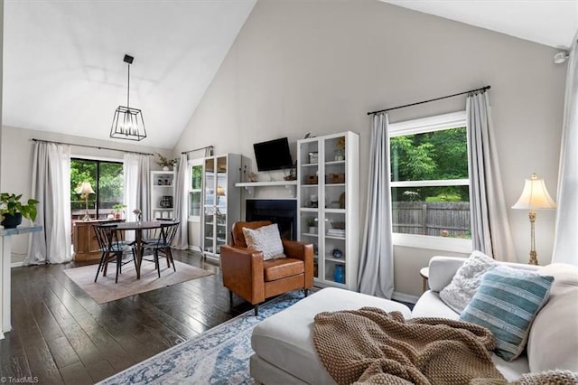 living room with a chandelier, a fireplace, hardwood / wood-style floors, and high vaulted ceiling