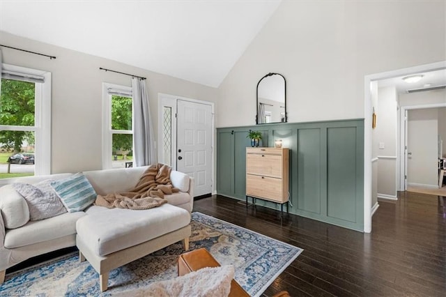 living area featuring dark wood-type flooring, a decorative wall, and high vaulted ceiling