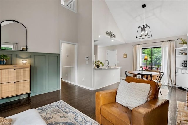 living area featuring a notable chandelier, visible vents, wood finished floors, and high vaulted ceiling