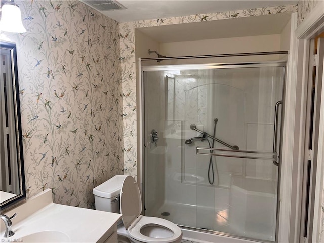 bathroom featuring a shower with shower door, toilet, and vanity