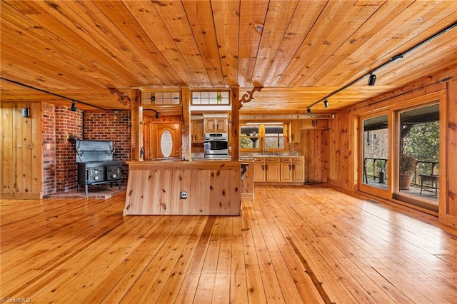 kitchen featuring wood walls, light hardwood / wood-style floors, a wood stove, and wooden ceiling