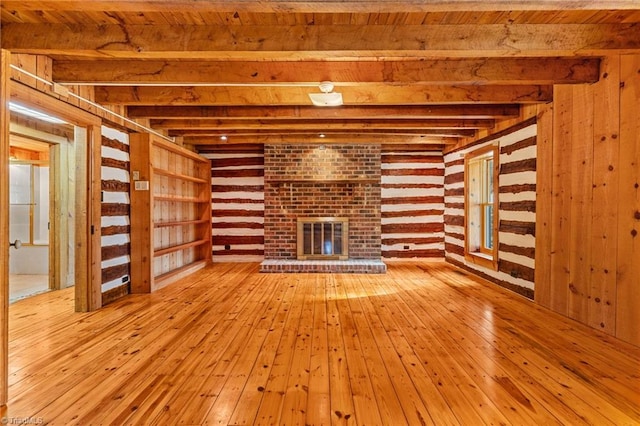 unfurnished living room featuring beam ceiling, a fireplace, wood ceiling, and light hardwood / wood-style floors