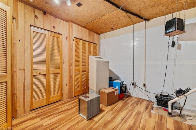 basement featuring wood walls and light wood-type flooring