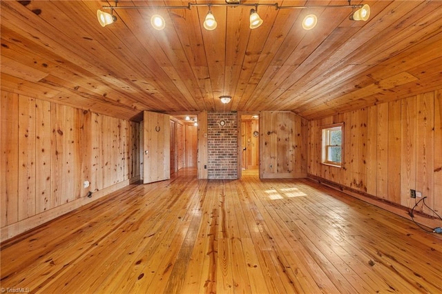 unfurnished living room with lofted ceiling, light hardwood / wood-style floors, wood ceiling, and wooden walls