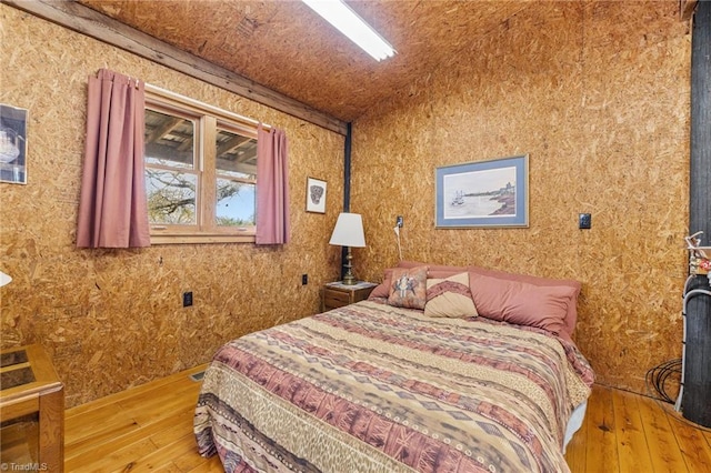 bedroom with wood-type flooring and vaulted ceiling