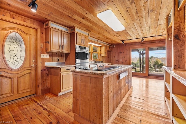 kitchen with wood walls, a center island, wood ceiling, and light wood-type flooring