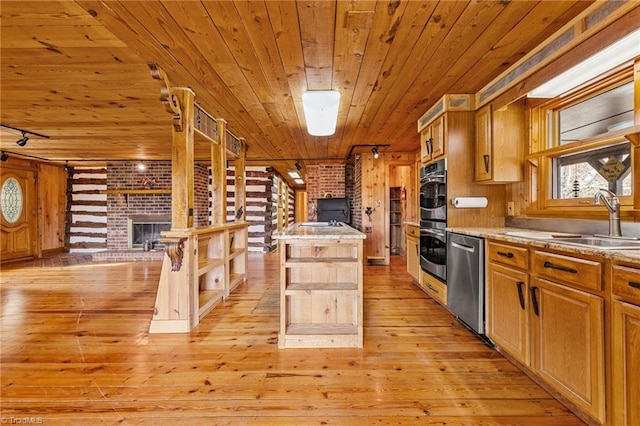 kitchen featuring a center island, sink, light wood-type flooring, appliances with stainless steel finishes, and brick wall