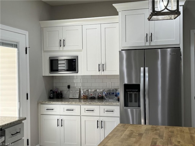 kitchen featuring stainless steel appliances, white cabinets, backsplash, and light stone countertops