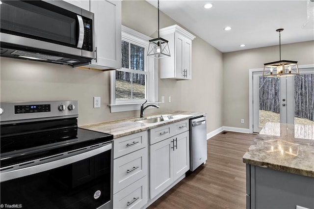 kitchen featuring white cabinetry, sink, stainless steel appliances, an inviting chandelier, and pendant lighting