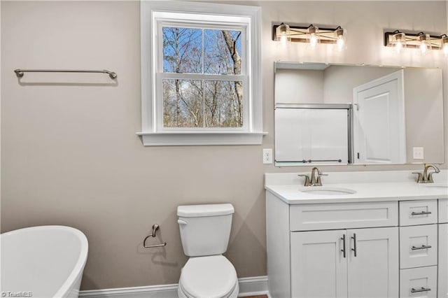 bathroom featuring a washtub, vanity, and toilet