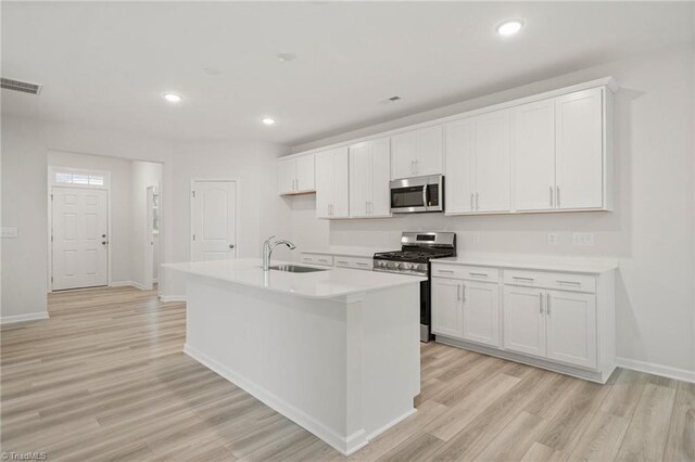 5365 Roshni Ter, Mcleansville, NC 27301 - kitchen featuring light countertops, white cabinetry, light wood-style floors, and stainless steel appliances