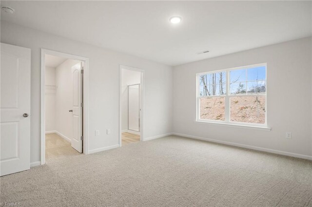 5365 Roshni Ter, Mcleansville, NC 27301 - unfurnished bedroom featuring a walk in closet, carpet, visible vents, and baseboards