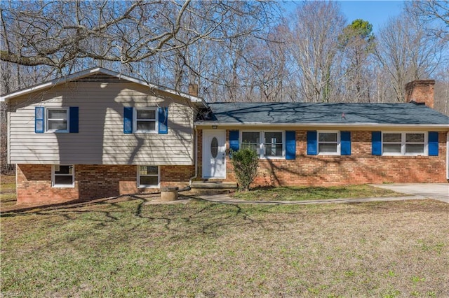 split level home with brick siding, a chimney, and a front yard