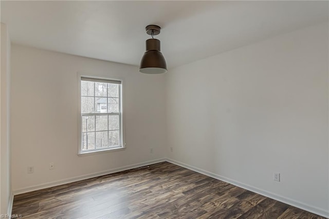 unfurnished room featuring baseboards and dark wood-style floors