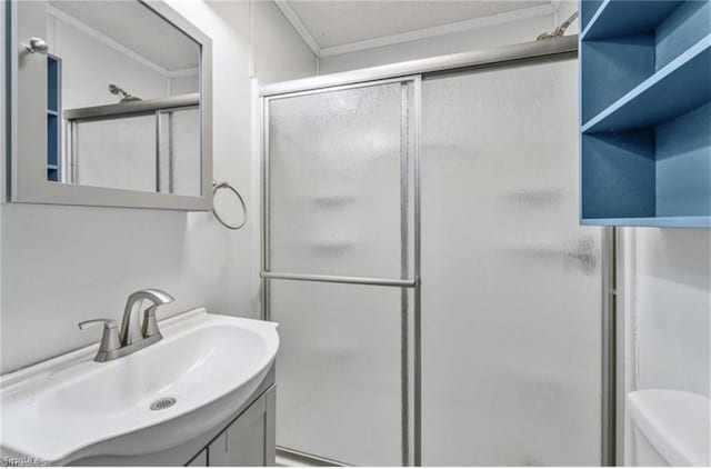 bathroom with crown molding, a shower with door, vanity, and toilet