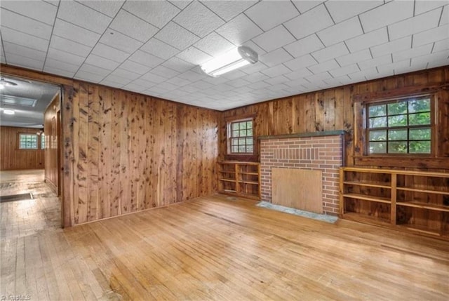 unfurnished room featuring light wood-type flooring, a fireplace, and plenty of natural light