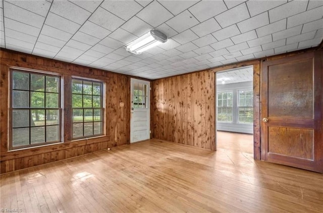 spare room featuring wood walls and light hardwood / wood-style flooring