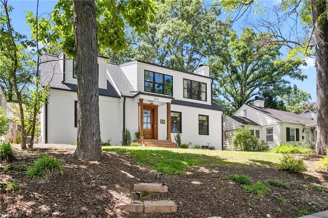 306 W Greenway Dr S, Greensboro, NC 27403 - view of front of house with stucco siding, a chimney, a front lawn, and roof with shingles