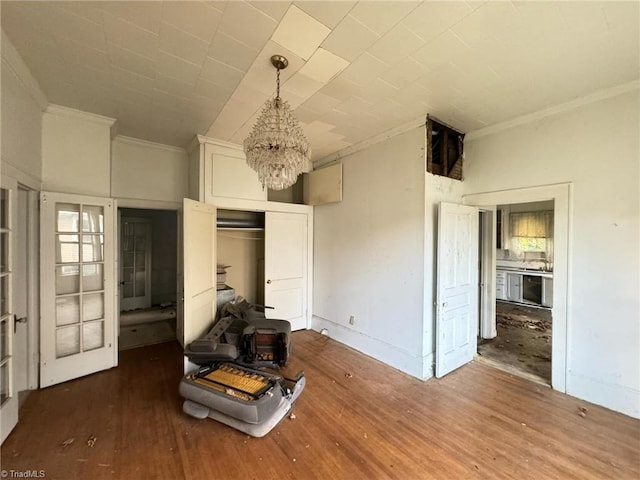 unfurnished bedroom with ornamental molding, hardwood / wood-style flooring, a closet, and a chandelier