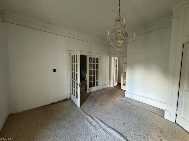 spare room with french doors, a notable chandelier, and carpet