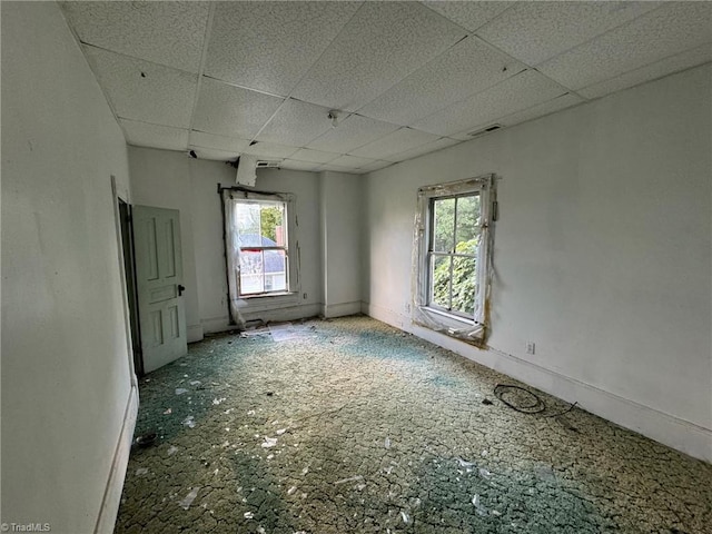 spare room featuring a drop ceiling and plenty of natural light