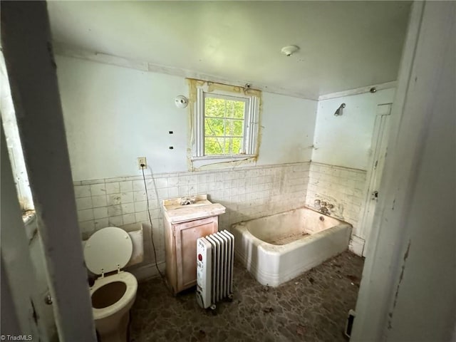 bathroom with tile walls, a washtub, radiator, vanity, and toilet