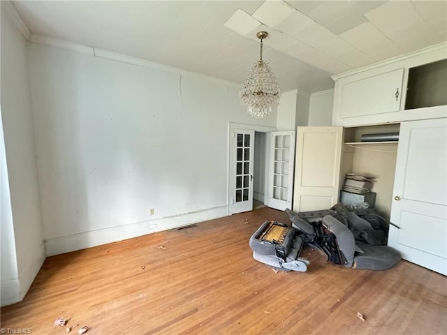 misc room featuring ornamental molding, wood-type flooring, and an inviting chandelier