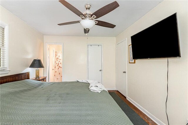 bedroom with baseboards, a ceiling fan, and dark wood-type flooring
