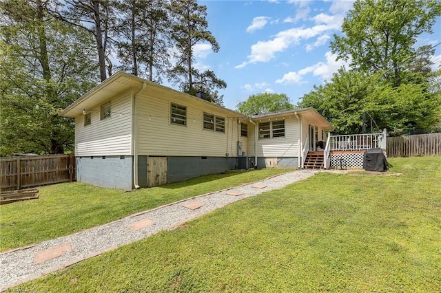 rear view of house with a deck, fence, a yard, and crawl space