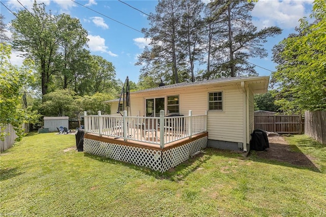 back of property featuring a deck, a fenced backyard, an outbuilding, a storage shed, and a lawn