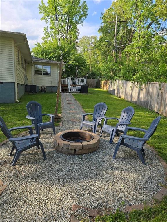 view of yard with fence, a fire pit, and a deck