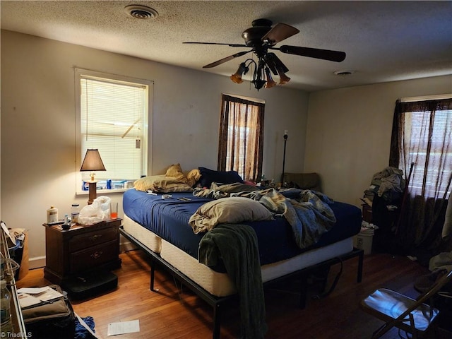 bedroom with ceiling fan, hardwood / wood-style floors, and a textured ceiling