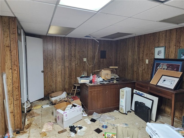 office featuring a drop ceiling and wooden walls