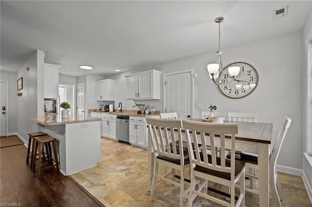 kitchen featuring white cabinetry, sink, light stone counters, light hardwood / wood-style flooring, and stainless steel dishwasher